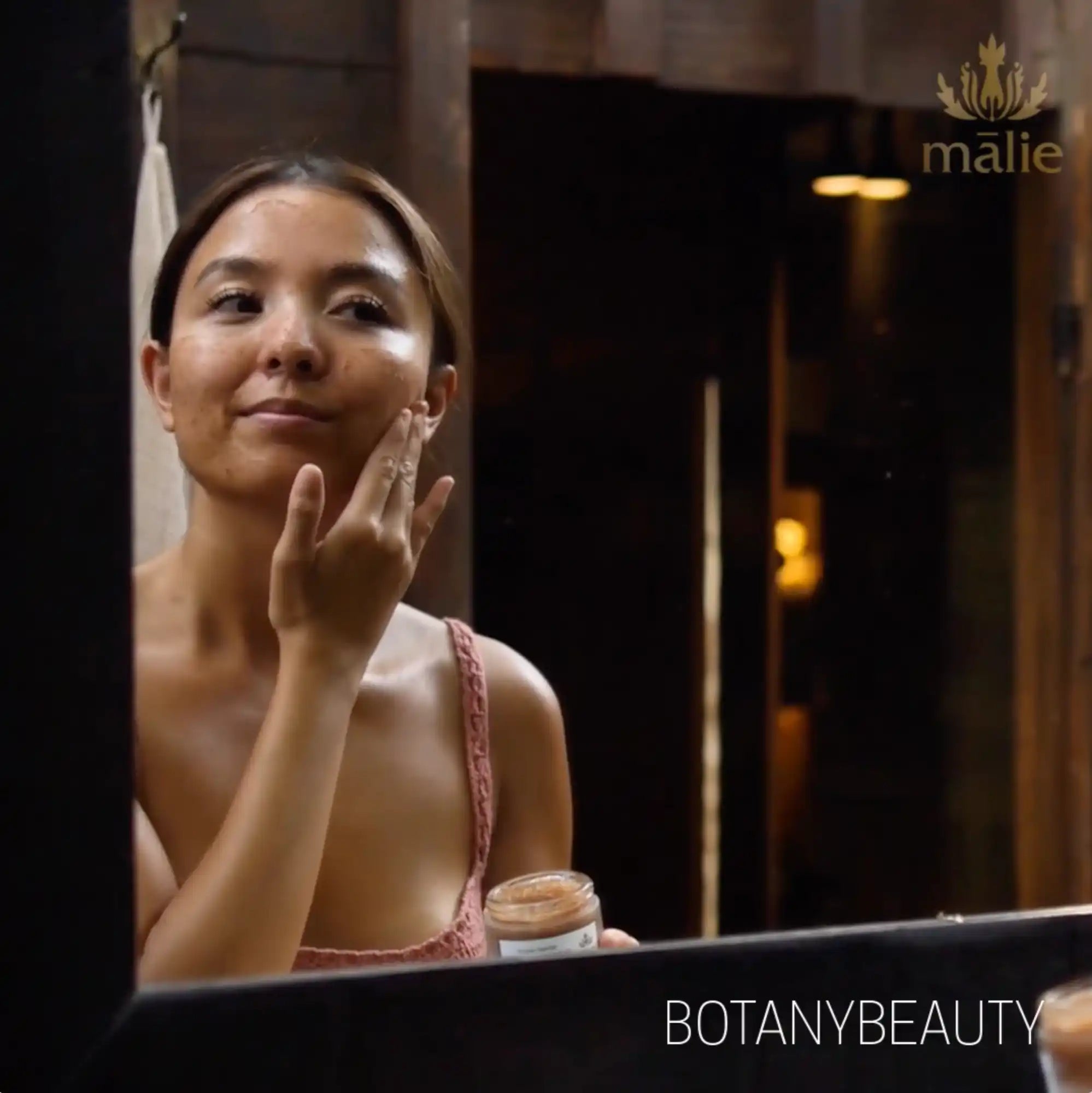 A person applying skincare product in front of a mirror.